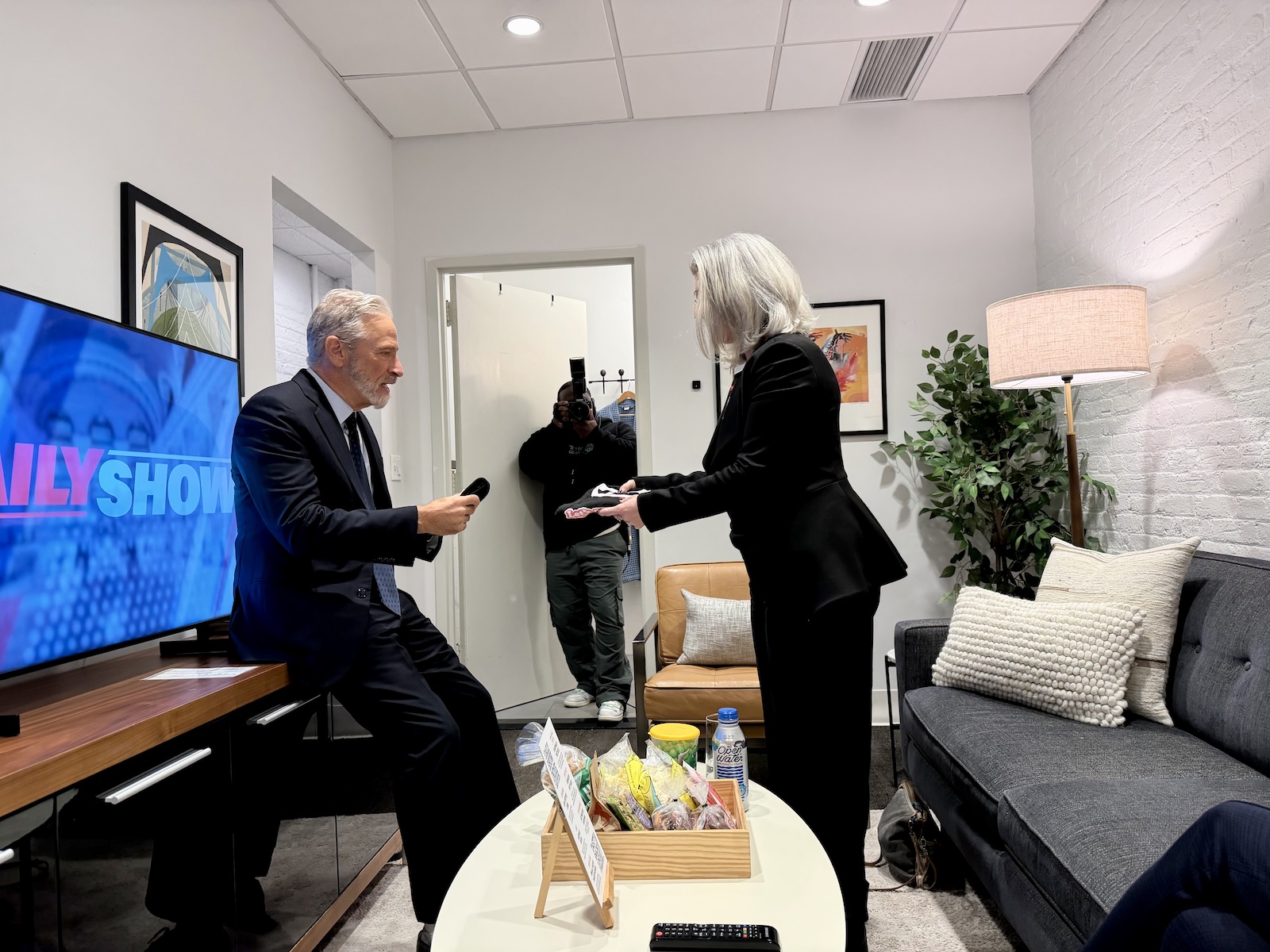 Cindy Cohn hands Jon Stewart a "Let's Sue the Government" t-shirt